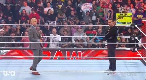 Superluchas - Un hombre de traje está parado en el ring con un cartel promocionando WWE RAW.