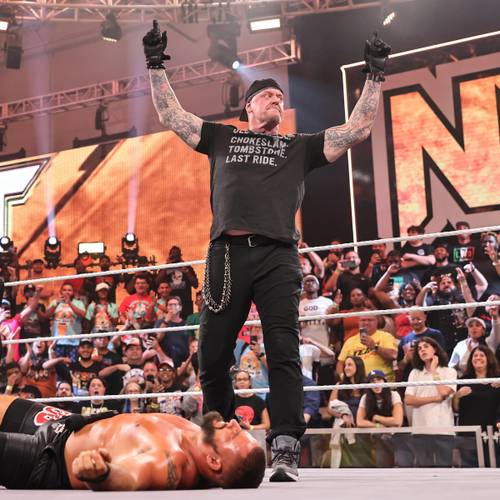Superluchas - Un luchador yace en el suelo frente a una multitud, mientras Tony Khan menciona a John Cena y The Undertaker.