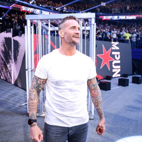 Superluchas - Un hombre con tatuajes parado frente a una multitud durante el Retorno de CM Punk en un evento de la WWE, brindando información sobre TKO y Triple H mientras era observado por Nick Khan y Vince McMahon.