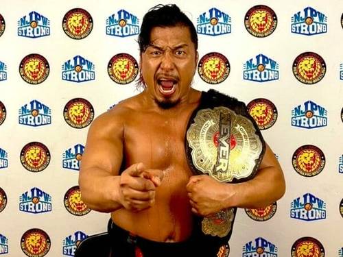 Superluchas - Shingo Takagi, un luchador, sosteniendo un cinturón de lucha libre frente a una pared.