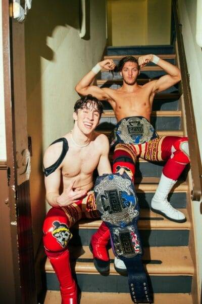 Superluchas - Dos luchadores posando en las escaleras con sus cinturones, mostrando la posible transición de GCW a AEW.