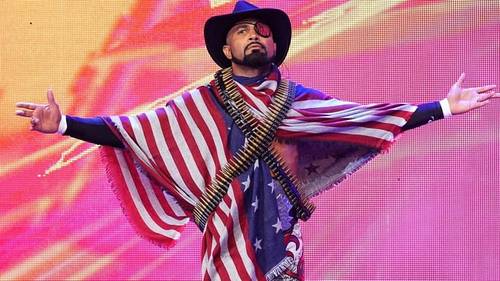 Superluchas - Un hombre vestido con una bandera estadounidense con los brazos extendidos muestra una exhibición patriótica.