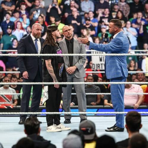 Superluchas - Adam Pearce, emocionado con la competencia Raw vs. SmackDown, le está dando la mano a un hombre de traje.