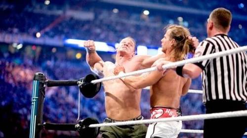 Superluchas - Dos luchadores, John Cena y Shawn Michaels, en un ring con un árbitro.