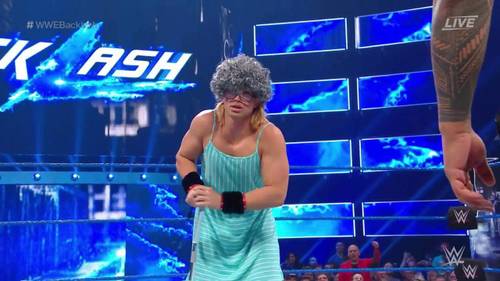 Superluchas - Una mujer con un vestido azul está parada frente a un ring de la WWE.