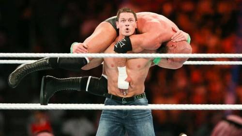 Superluchas - John Cena, un luchador, está siendo levantado por otro luchador en una emocionante demostración de fuerza y trabajo en equipo.
