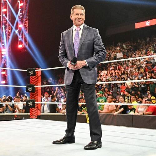 Superluchas - Vince McMahon, vestido con traje, parado frente a un ring de la WWE durante el evento Royal Rumble.