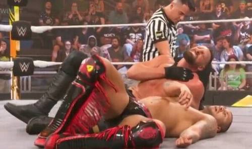 Un luchador tirado en el suelo con un árbitro durante WWE NXT.