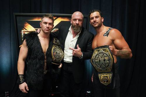Superluchas - Tres luchadores posan orgullosos para una fotografía mostrando sus cinturones de campeonato.