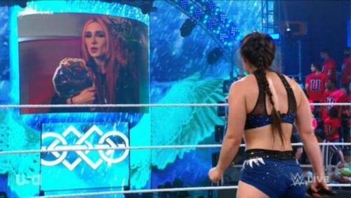 Superluchas - Una mujer en bikini está parada frente a un televisor que muestra WWE NXT.