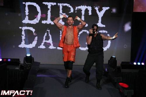 Superluchas - Dos luchadores, Dirty Dango y un luchador firmado por TNA, parados en un escenario con las palabras Dirty Daddy.
