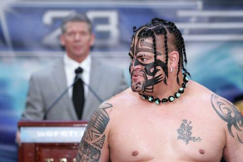 Un luchador tatuado parado frente a un micrófono amenaza a Umaga en la WWE.