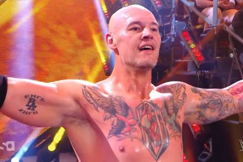 Superluchas - Baron Corbin, un luchador tatuado, está de pie con los brazos extendidos frente a una multitud que lo vitorea.