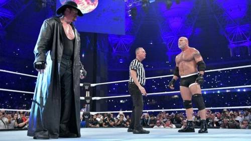 Superluchas - Dos luchadores, Undertaker y Goldberg, de pie en un ring.