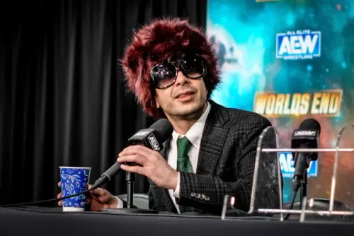 Superluchas - Tony Khan, un hombre de traje y gafas, ofrece una conferencia de prensa para responder a los rumores de acoso que involucran a Chris Jericho.
