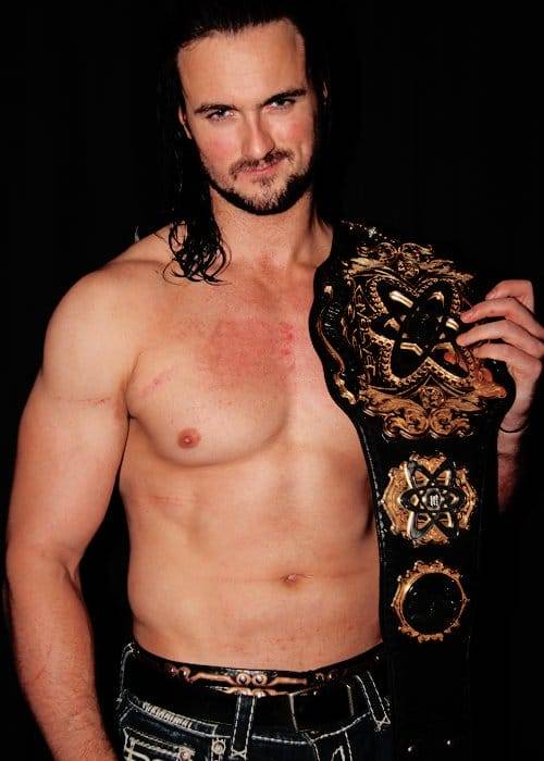 Superluchas - McIntyre, un hombre de pelo largo, sostiene con orgullo un cinturón de lucha libre.