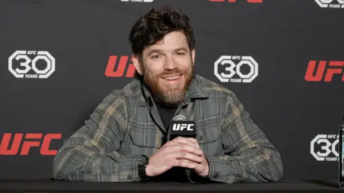 Superluchas - Jim Miller sentado frente a un micrófono en una conferencia de prensa de UFC.