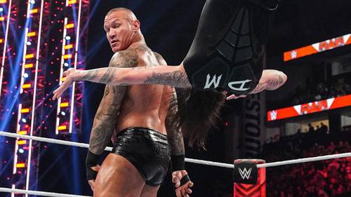 Superluchas - Un luchador está realizando un impresionante giro en el ring bajo la atenta mirada de Kurt Angle.