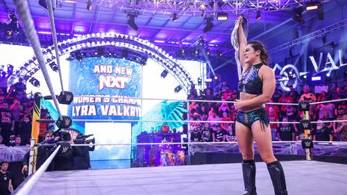 Superluchas - Una mujer en un ring de lucha libre con los brazos levantados en el aire, mientras Drew McIntyre aplaude a Lyra Valkyria por convertirse en la nueva campeona de NXT.
