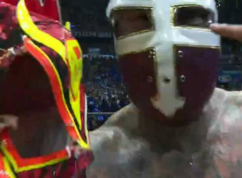 Un luchador sostiene una máscara durante el combate entre Templario y Dragón Rojo Jr.