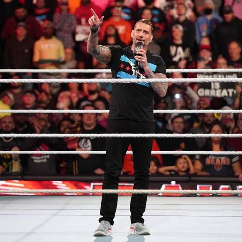 Superluchas - Booker T predice que WWE no será como AEW con CM Punk mientras un hombre sostiene un micrófono en un ring de lucha libre.