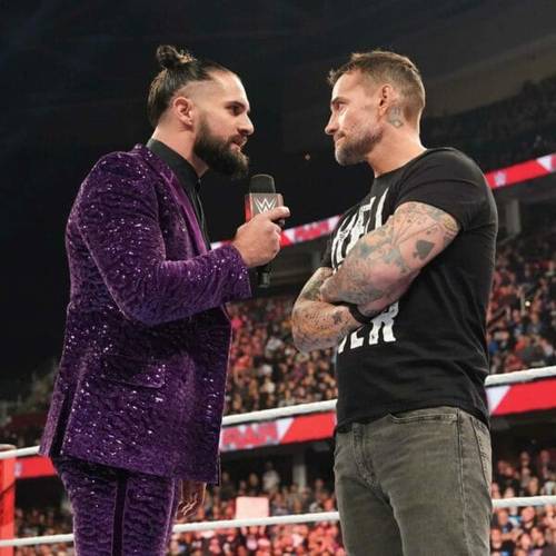 Superluchas - Dos luchadores, Seth Rollins y CM Punk, con trajes morados hablando entre sí en el mundo de la WWE.