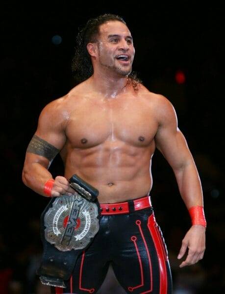 Superluchas - Tama Tonga sosteniendo un cinturón frente a una multitud durante la confirmación de las conversaciones de la WWE.