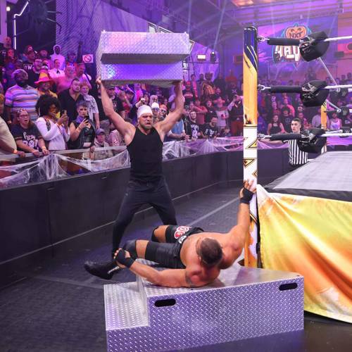 Superluchas - Dos luchadores en un ring de lucha libre con una caja frente a ellos mostrando el proceso de crecimiento y aprendizaje de Von Wagner en NXT.