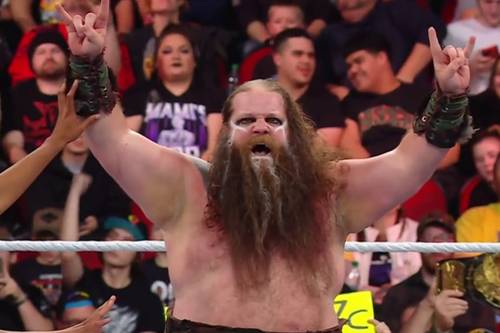 Superluchas - Akira Tozawa, un hombre con barba, levanta las manos en el aire.