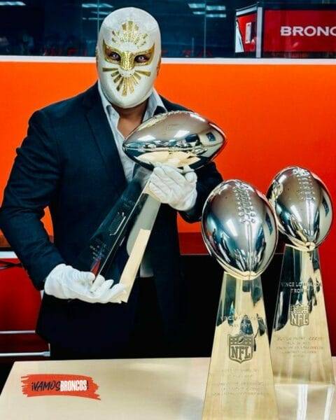 Superluchas - Un hombre con una máscara sostiene con orgullo dos trofeos de la NFL.