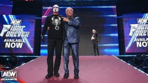 Superluchas - Dos luchadores, Ric Flair y Sting, uno al lado del otro en un escenario.